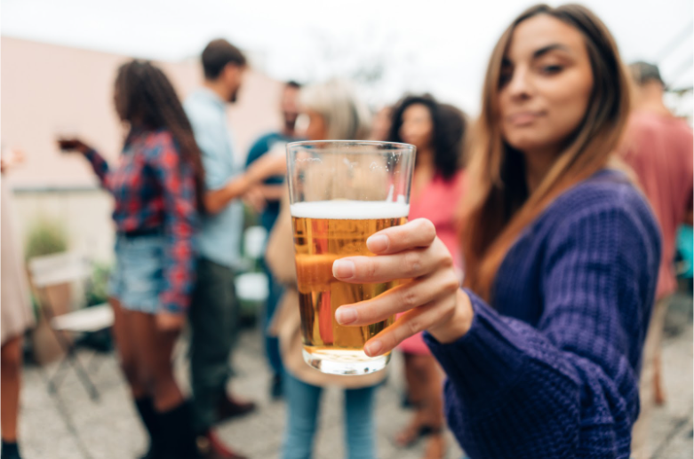 Girl offering a glass of beer containing alcohol